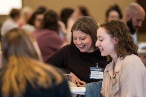 Two women at conference smiling while working at table